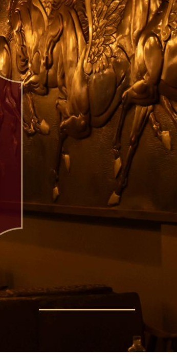 The gold-relief Pegasus mural inside the dining club, warm amber light